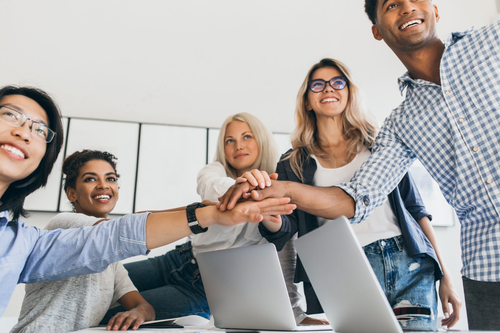 Asian businessman in leather wristwatch holding hands with partners and smiling. Indoor portrait of team of office workers having fun before big project.